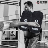 Trainer using Rewon camouflage MMA kick pads during boxing or martial arts session in a gym setting.